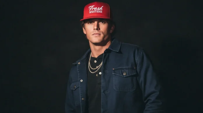 Parker McCollum wearing a red cap and denim jacket in a studio portrait